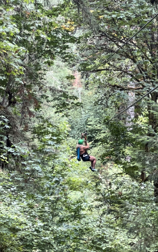 woman ziplining through trees
