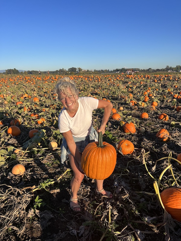 woman holding large pumpkin in pumpkin patch